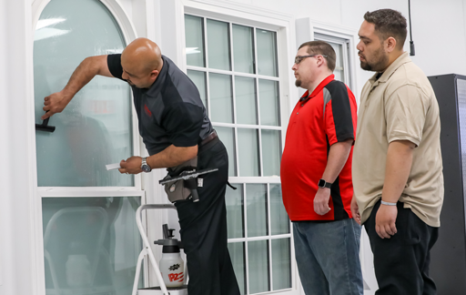 Instalador de película para vidrios arquitectónica mostrándoles a los aprendices la técnica de instalación correcta 